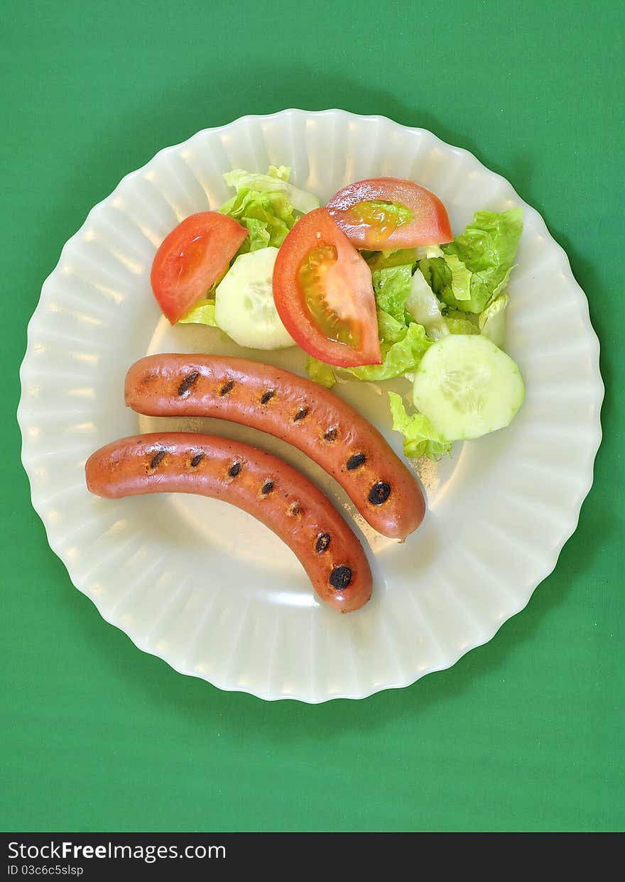 Plate of sausages and lettuce and tomato salad. Plate of sausages and lettuce and tomato salad