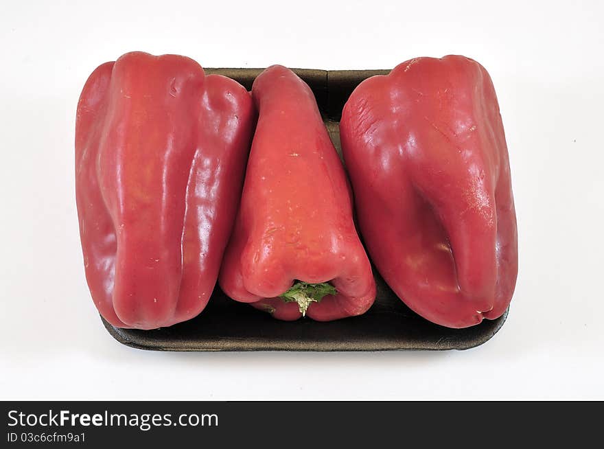 Three red peppers in supermarket tray