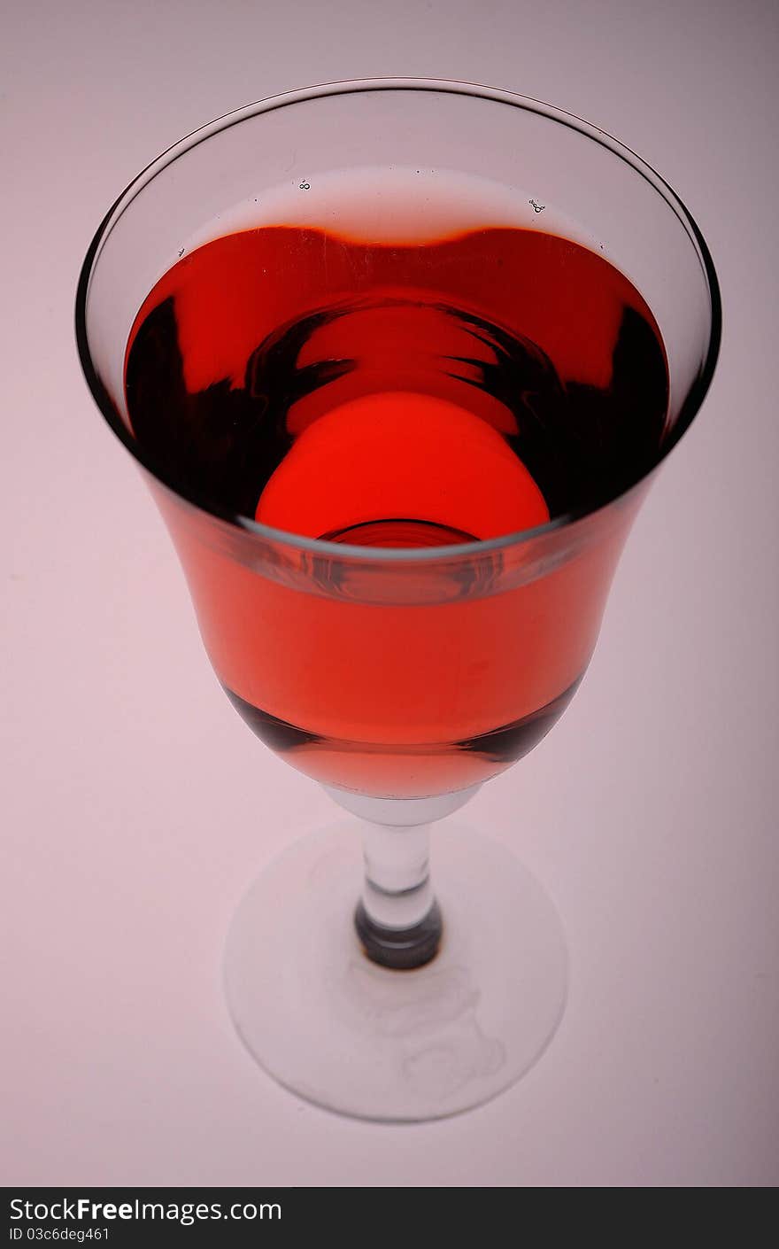 A cool glass of rose wine against a gray backdrop lit from below.