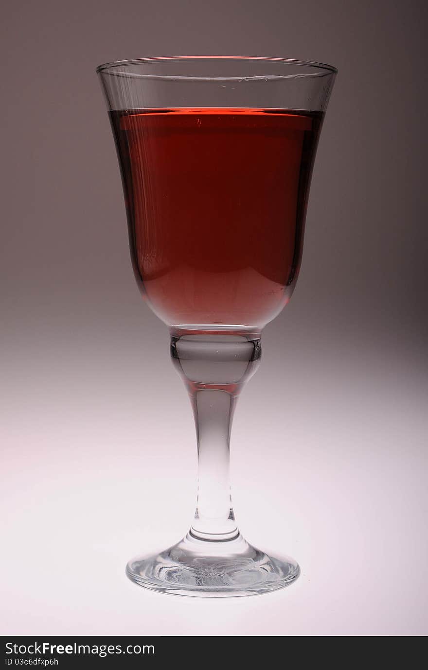 A cool glass of rose wine against a contoured gray backdrop lit from below.