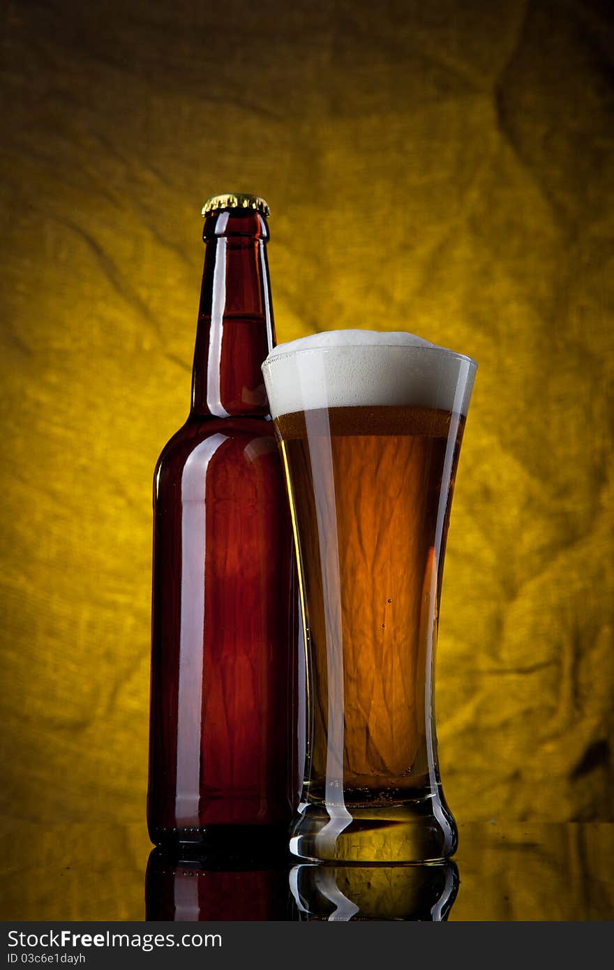 Beer in glass with bottle on yellow background