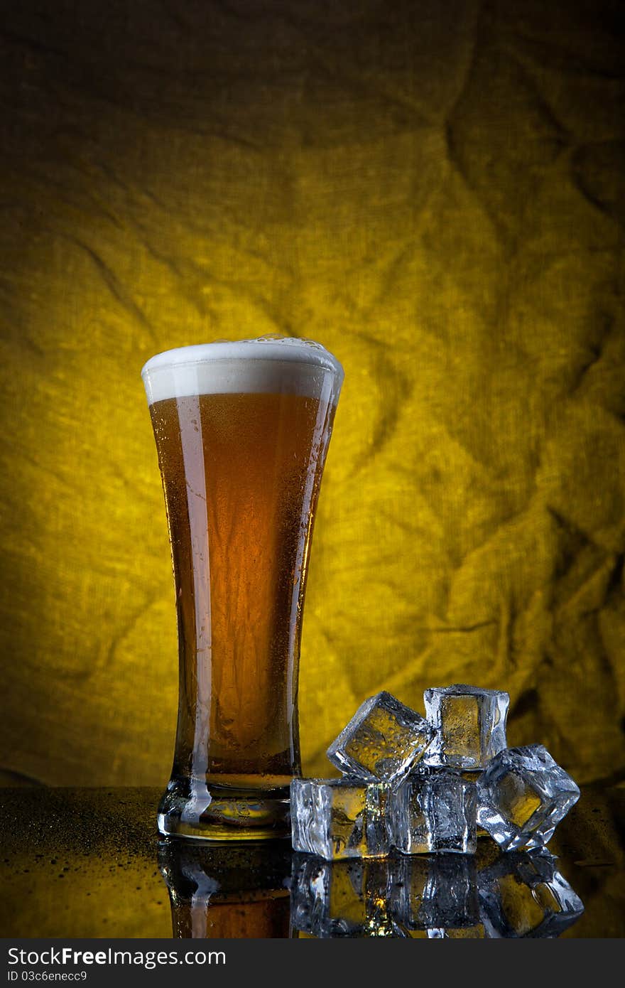 Beer In Glass With Ice Cubes On Yellow Background