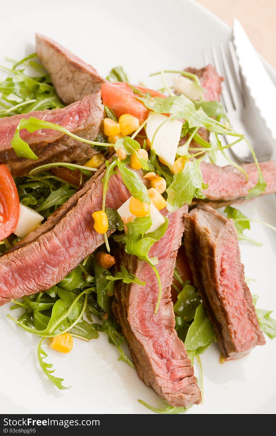 Delicious slices of meat with rocket salad and toamtoes