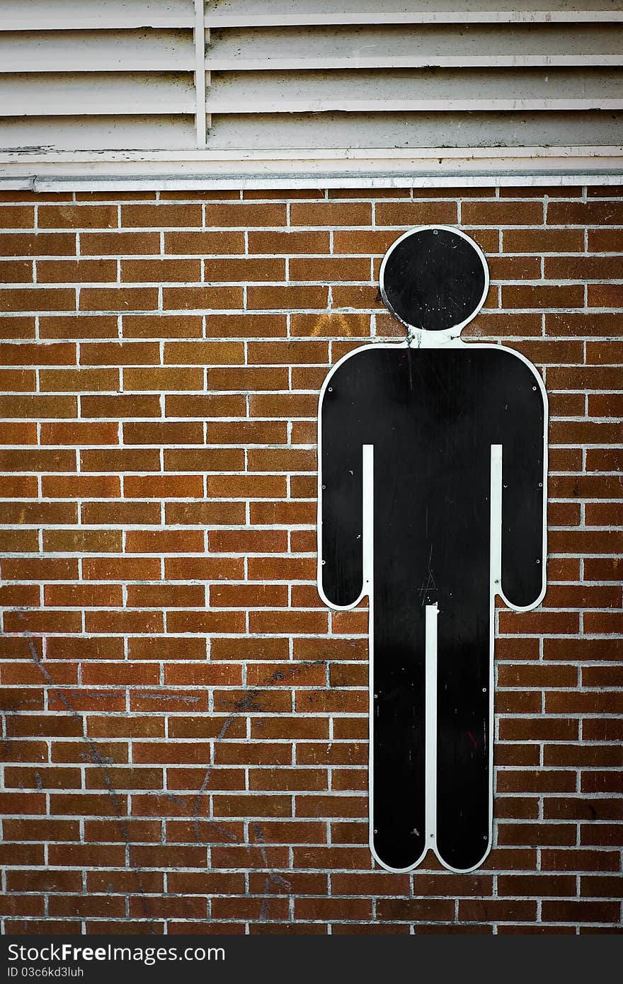 A human male AIGA international man symbol affixed to a red-brick wall. A human male AIGA international man symbol affixed to a red-brick wall