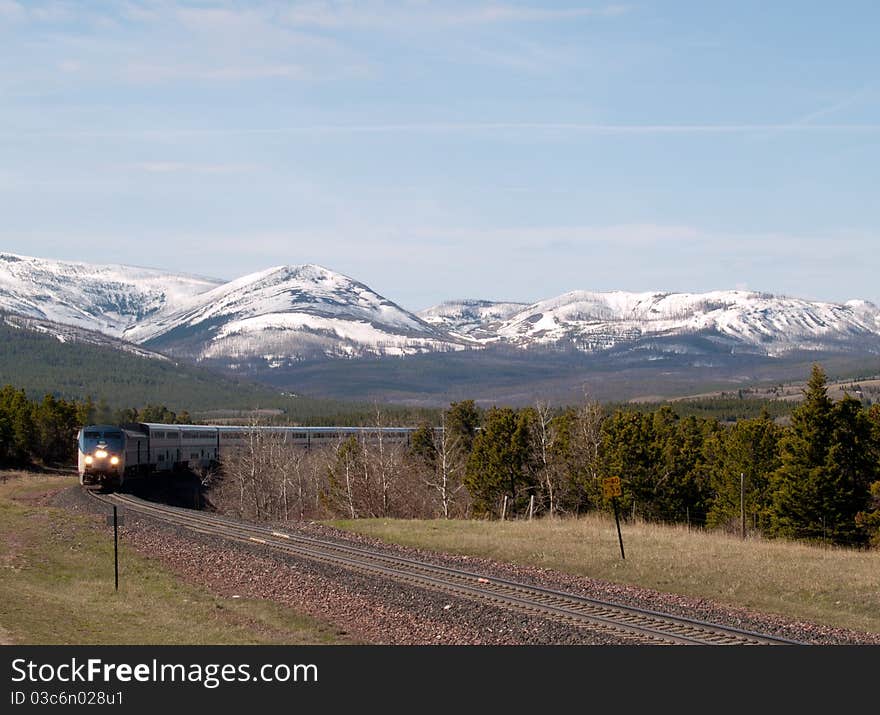 This image of the passenger train coming around the bend in the tracks with the snowcapped mountains in the background was taken in NW Montana.