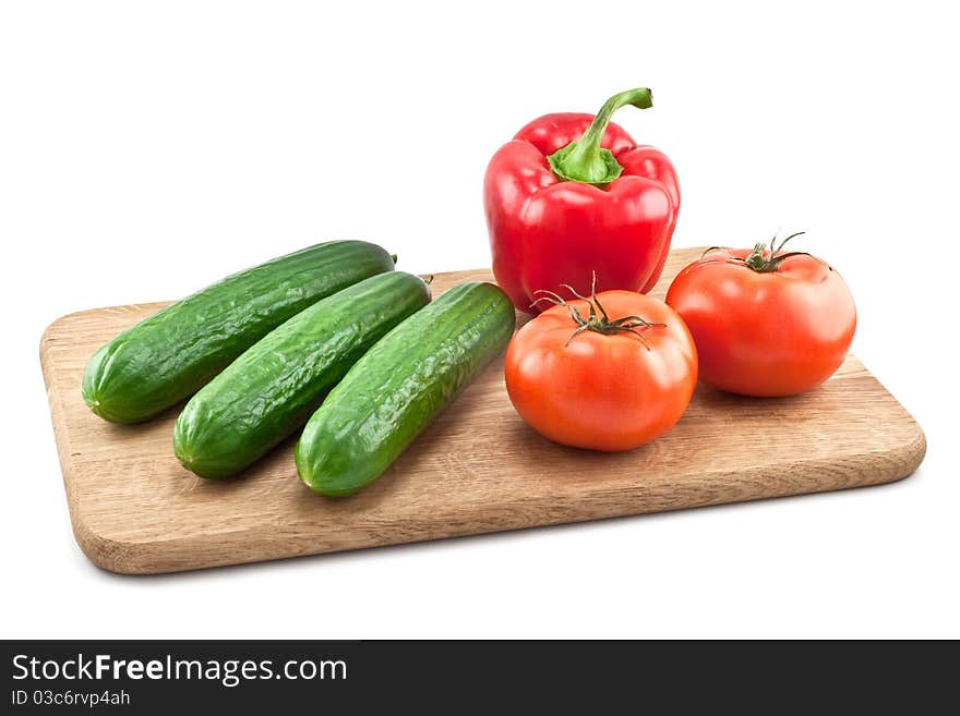 Cucumbers, tomatoes and peppers on wooden board isolated on white background