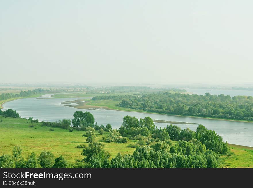 Channel, located between the field and forest, summer landscape, haze in the background, the photograph is a place for advertising slogan, mark or logo. Channel, located between the field and forest, summer landscape, haze in the background, the photograph is a place for advertising slogan, mark or logo