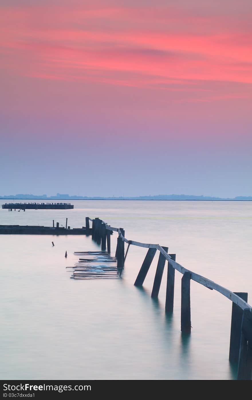 Colorful sunset, and the old bridge into the water