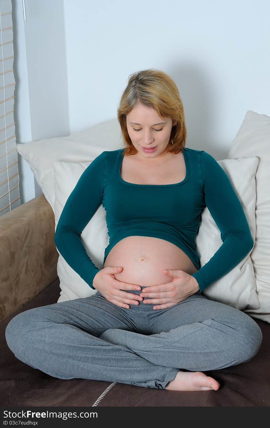 Young pregnant woman with hands on her abdomen.