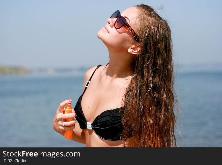 Pretty young caucasian woman spraying on the body against blue sky