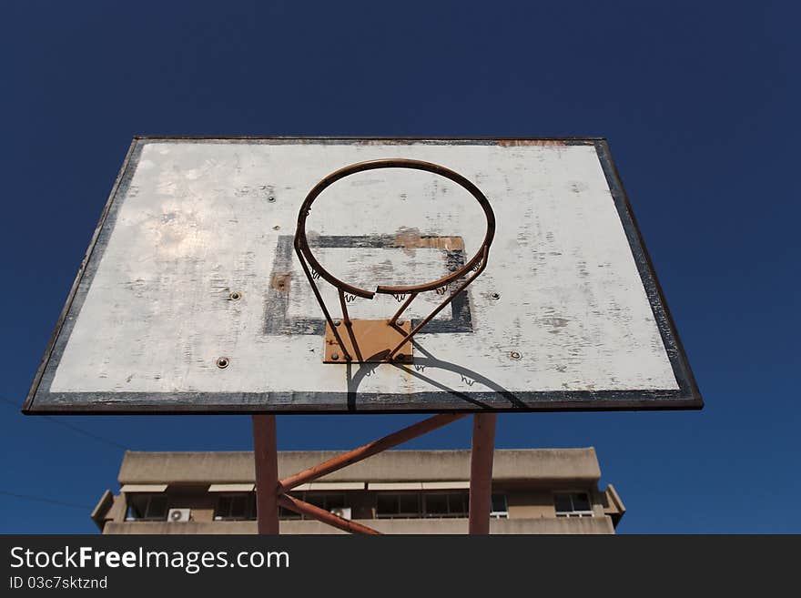 Old Broken Basketball Hoop Against The Sky