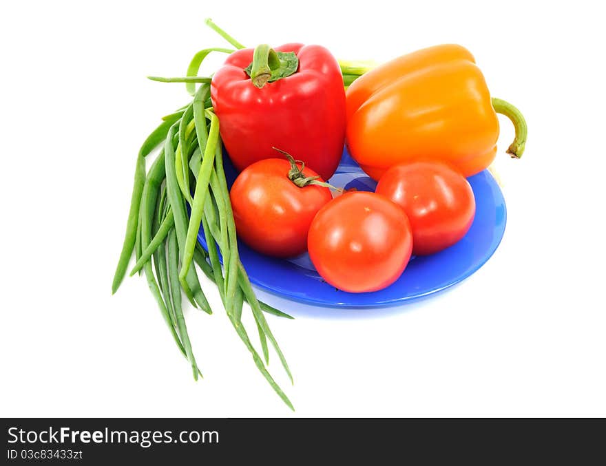 Vegetables on blue plate, isolated on a white background. Vegetables on blue plate, isolated on a white background