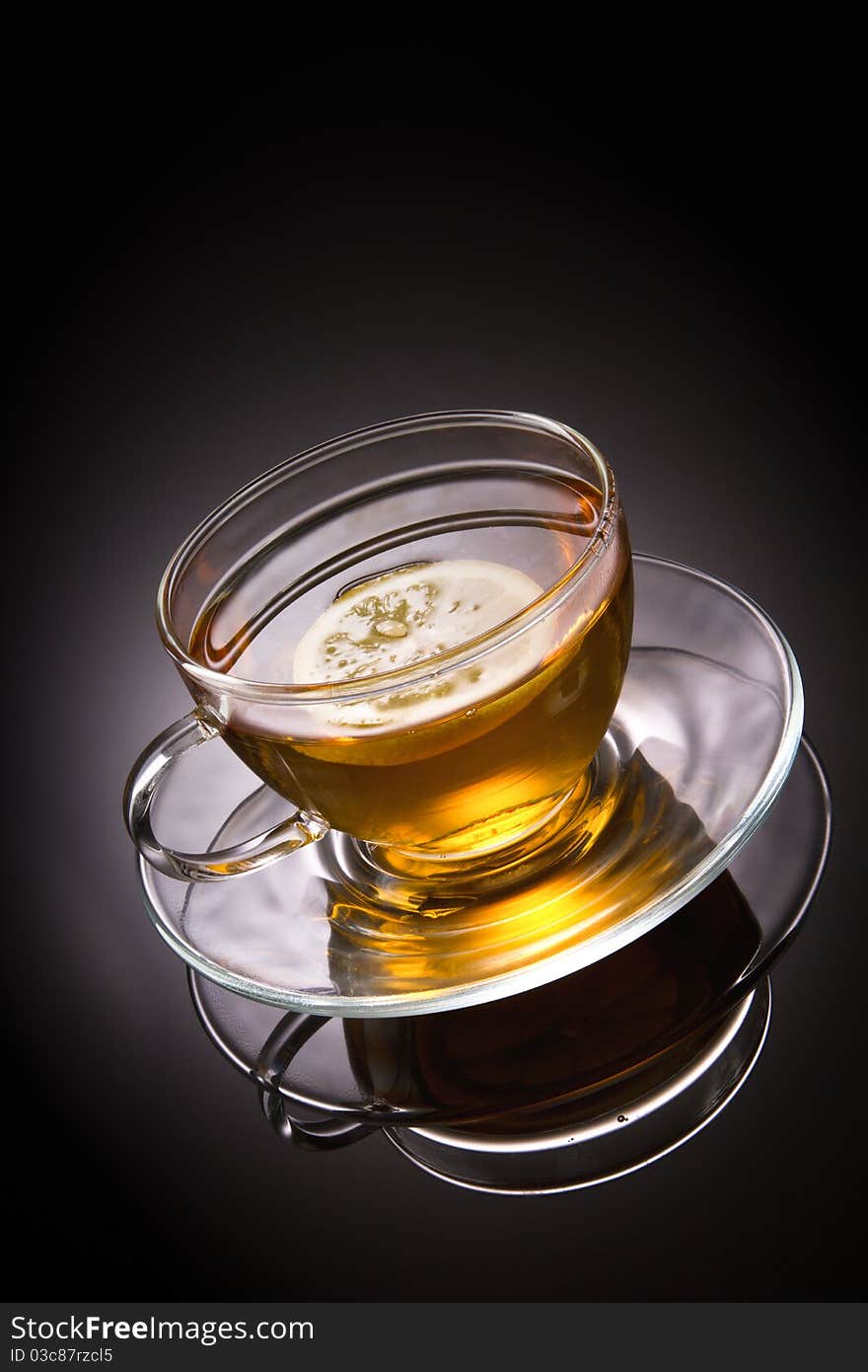 Tea with lemon in glass cup on grey background