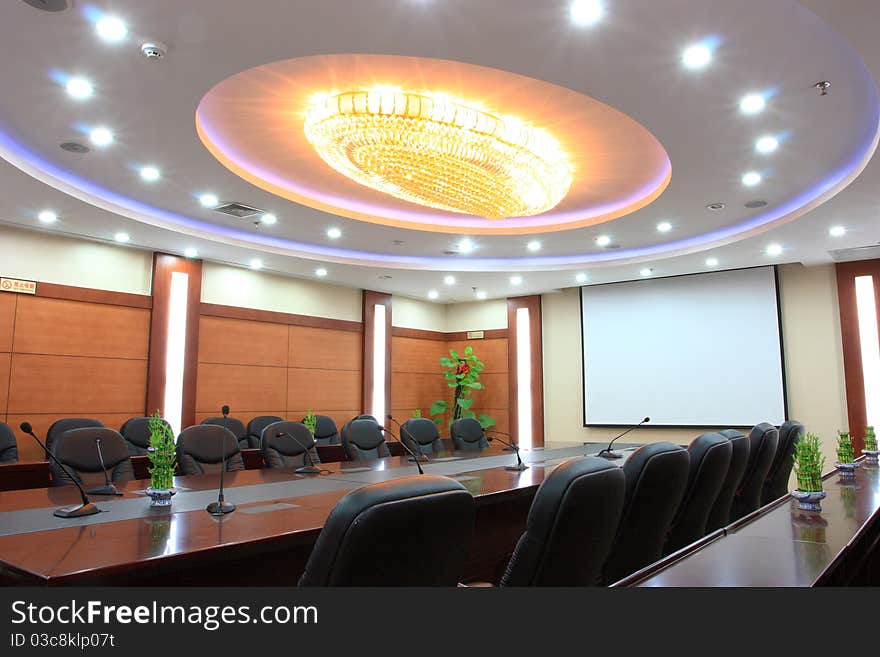 A empty meeting room with a table and chairs.A chandelier at ceiling. A empty meeting room with a table and chairs.A chandelier at ceiling.