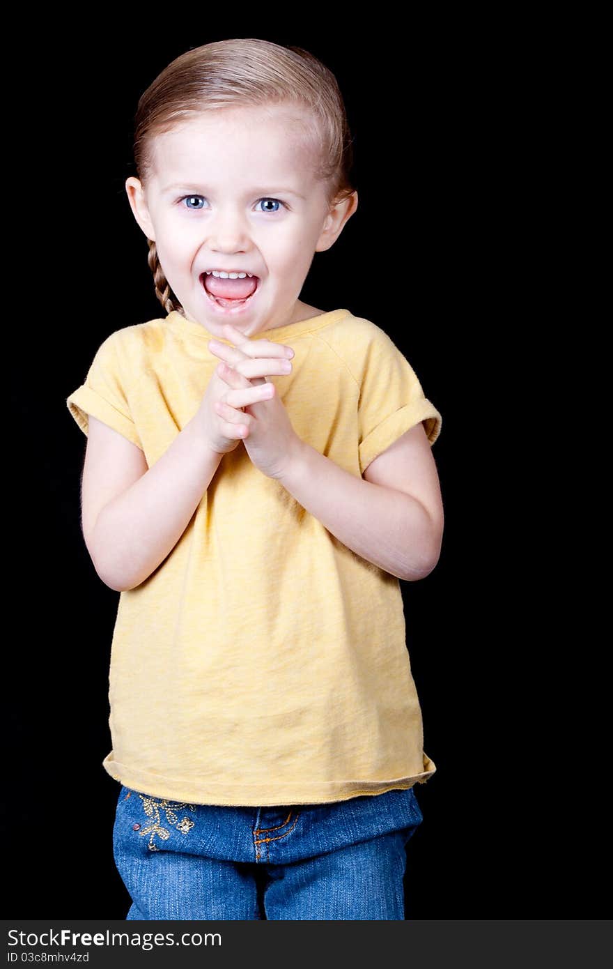 A girl with her hands clasped and her face shows a lot of excitement.