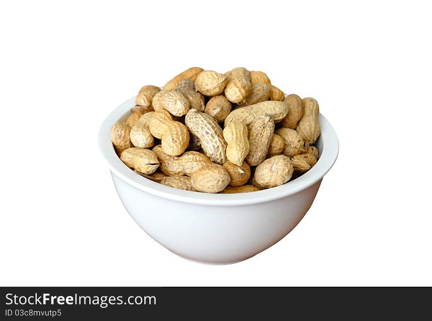 A white dish full of peanuts in nutshell