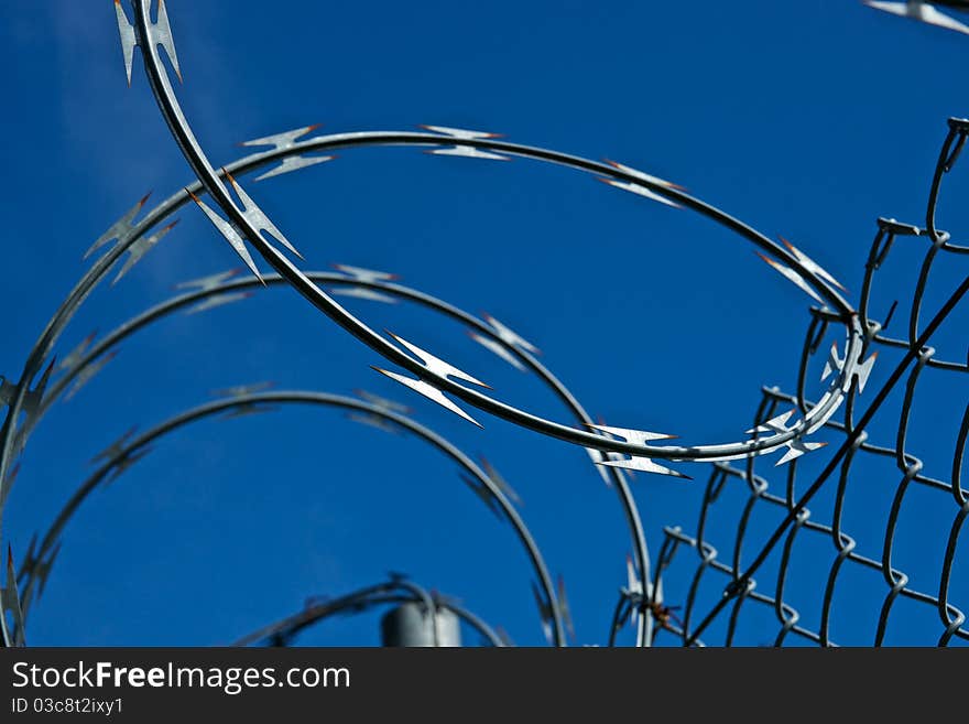 Razor wire keeps criminals from climbing over the fence of the off-limits facility. Razor wire keeps criminals from climbing over the fence of the off-limits facility.