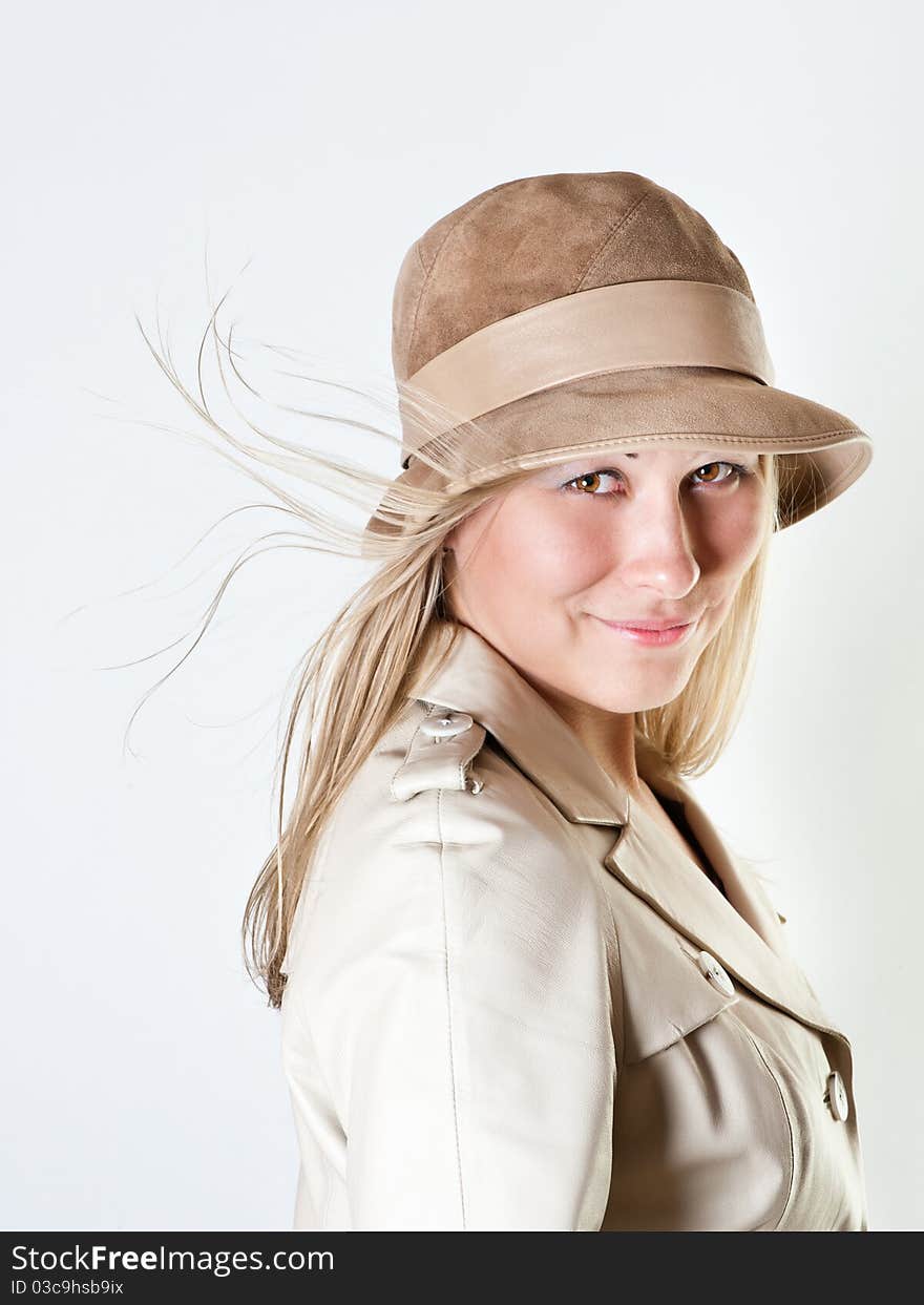 Portrait of a woman in a leather coat and a hat with her hair blown by the wind. Portrait of a woman in a leather coat and a hat with her hair blown by the wind