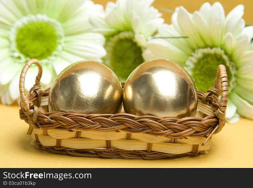 Two gold Easter eggs are in a wicker basket. Easter Traditions. Two gold Easter eggs are in a wicker basket. Easter Traditions