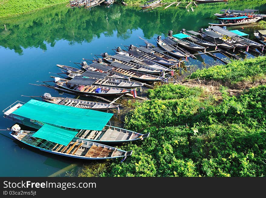 Group of long tailed boats floating on green emeral lake.