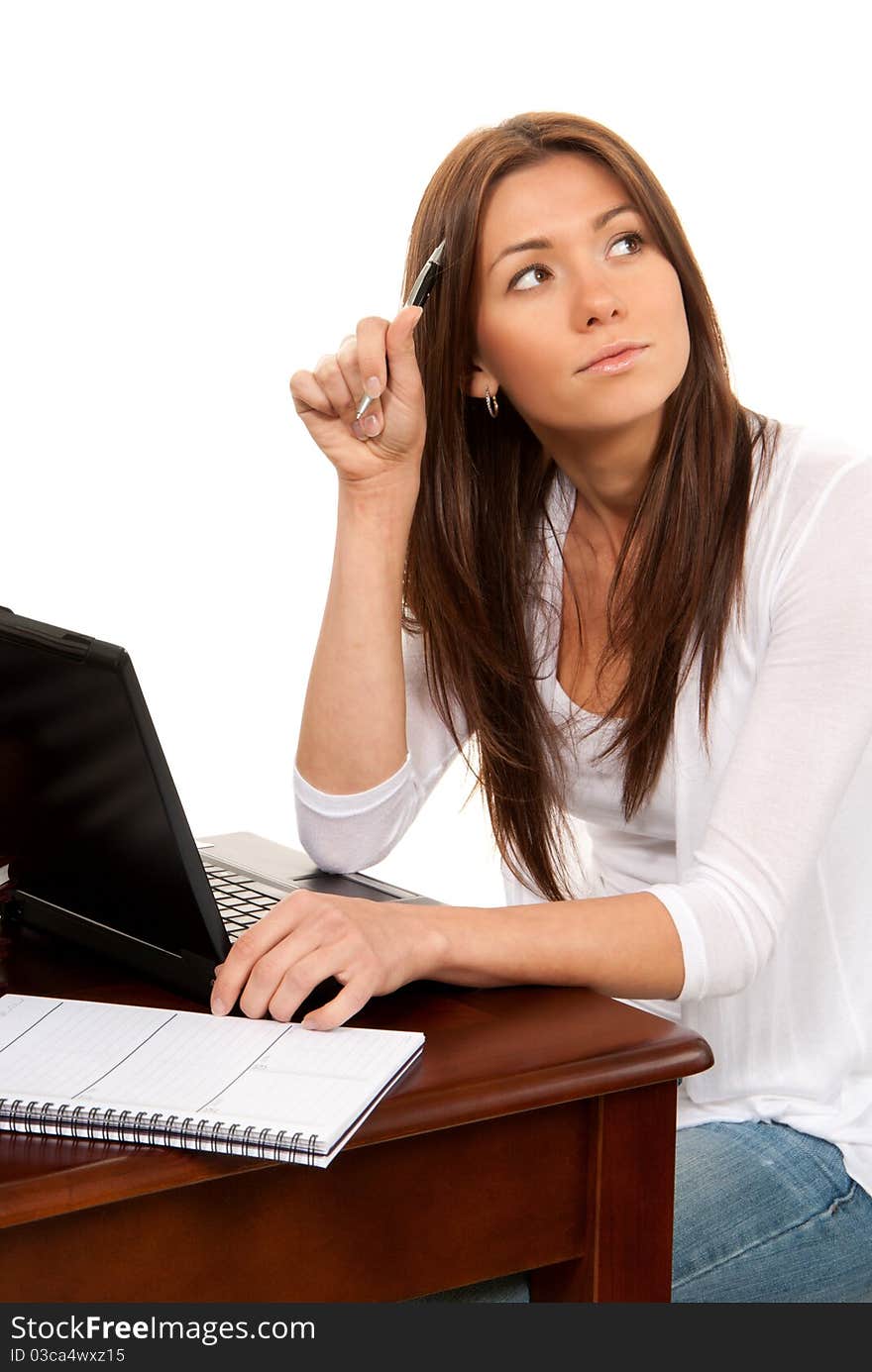 Pretty businesswoman thinking, with laptop on the table and holding pen in hand at work office place on a white background. Pretty businesswoman thinking, with laptop on the table and holding pen in hand at work office place on a white background