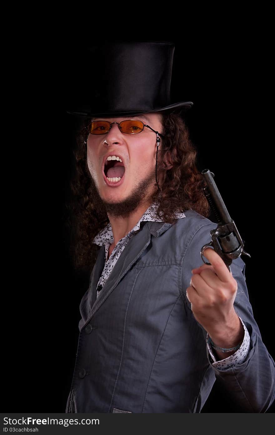 Emotional portrait of the young man in a black top-hat with a pistol in hand. Emotional portrait of the young man in a black top-hat with a pistol in hand