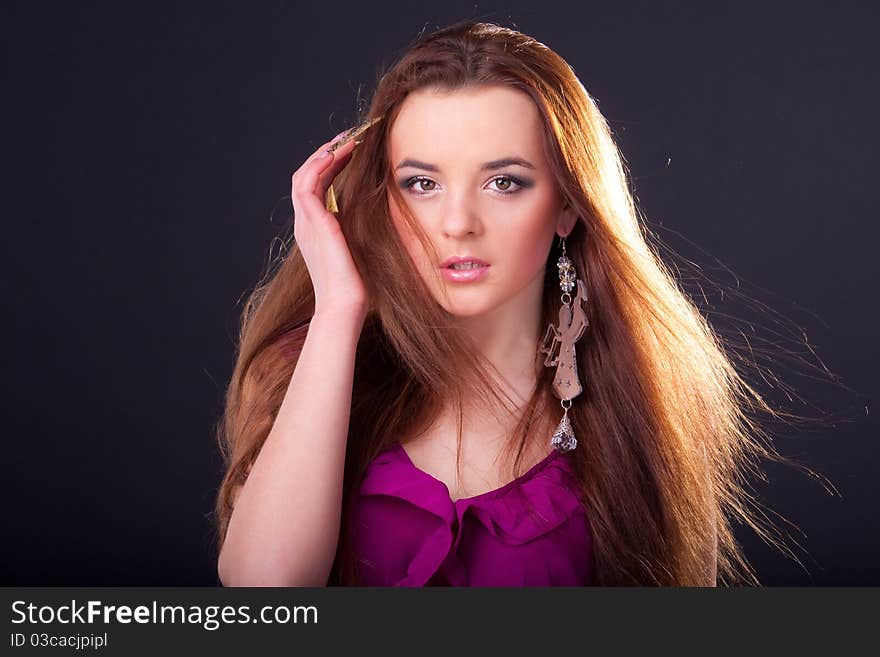 Beautiful long-haired brunette in a dress of fuchsia with sparkle earring. Beautiful long-haired brunette in a dress of fuchsia with sparkle earring