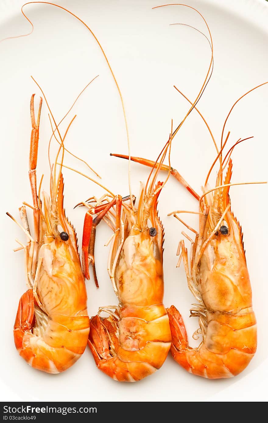 Three grilled prawns on white plate