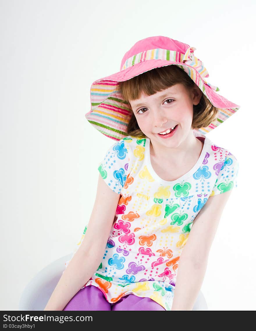 Little girl wearing colorful hat, sitting, leaning, isolated on white. Little girl wearing colorful hat, sitting, leaning, isolated on white.