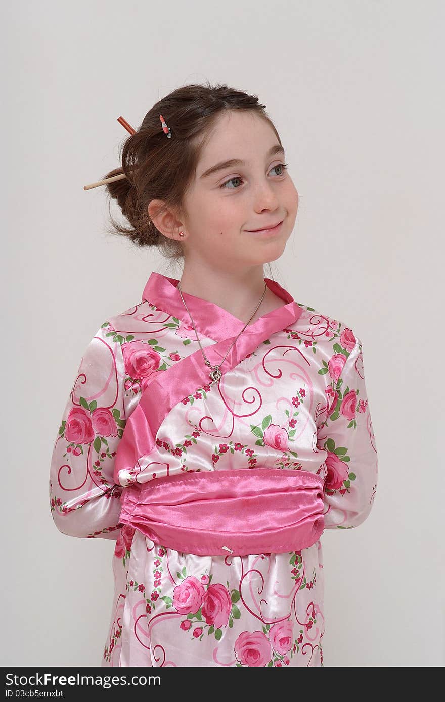 Cute smiling girl in Japanese masquerade costume standing with hands behind her back