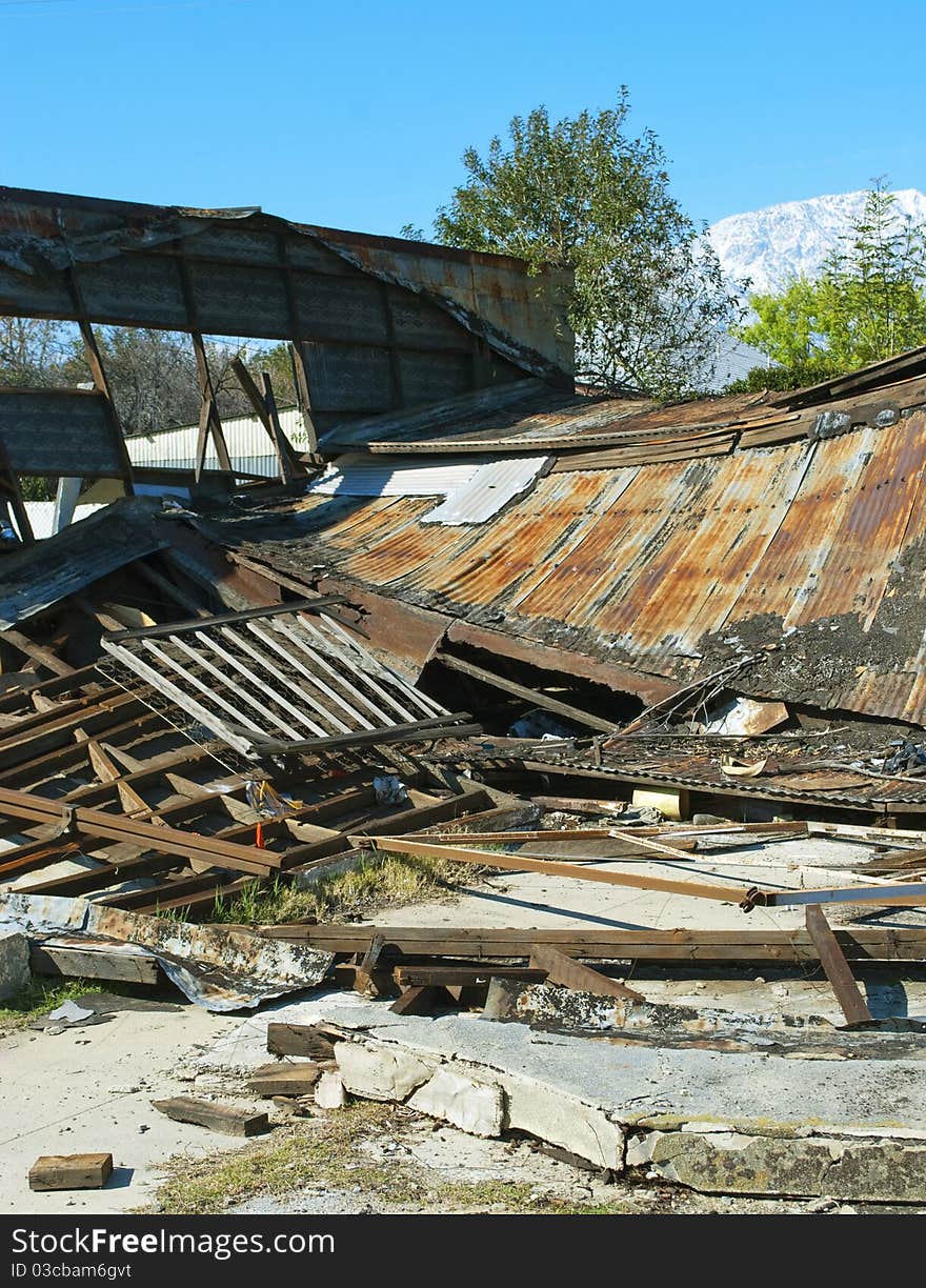 An ugly delapitated building that has collapsed with beautiful snow-capped mountains in the background. An ugly delapitated building that has collapsed with beautiful snow-capped mountains in the background