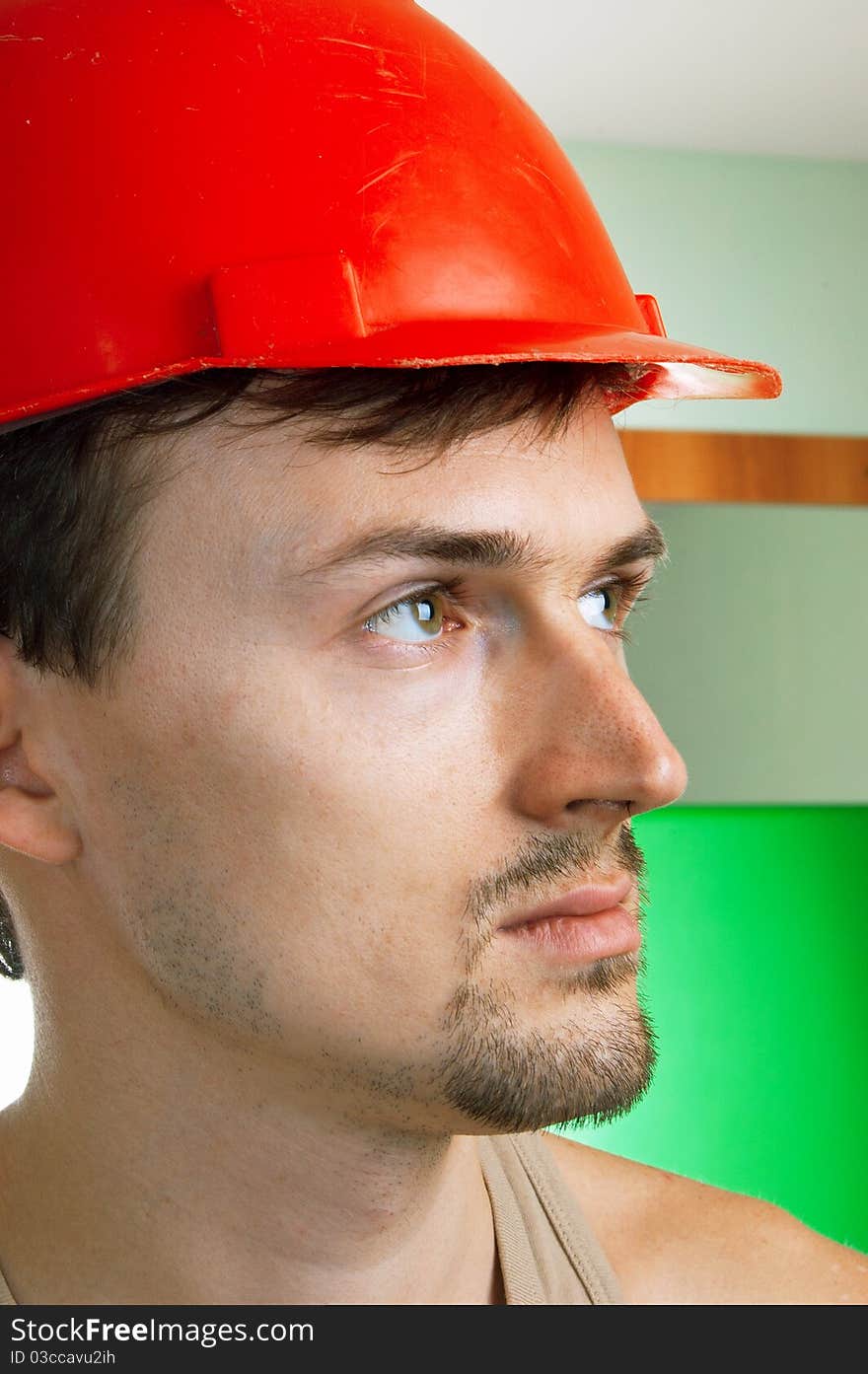 Young worker in a red building helmet on abstract background