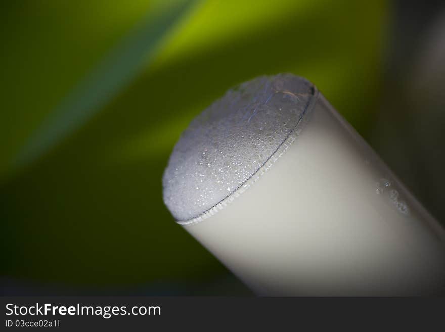 A glass full of milk on green background.