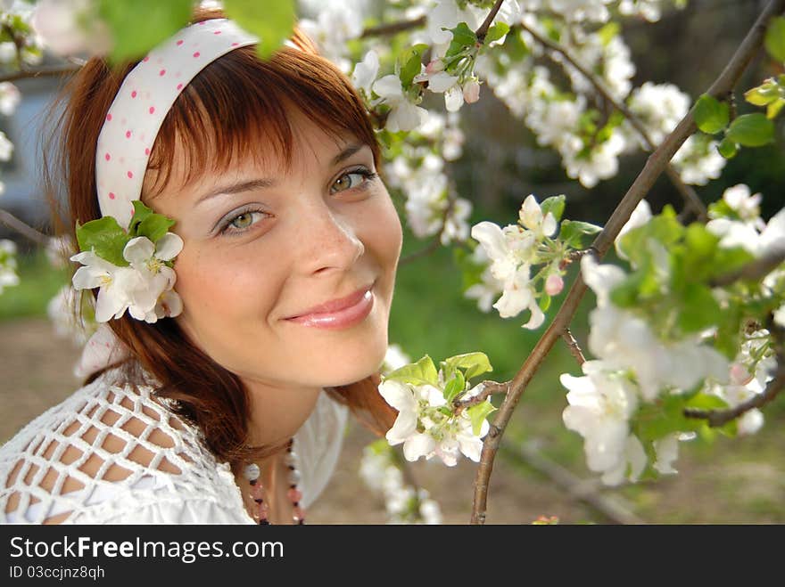 Beautiful, young woman smiles. Beside her, a branch of apple blossoms. Beautiful, young woman smiles. Beside her, a branch of apple blossoms