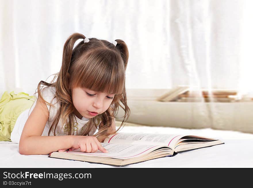 Lovely little girl, reading a book, on the bed. Lovely little girl, reading a book, on the bed