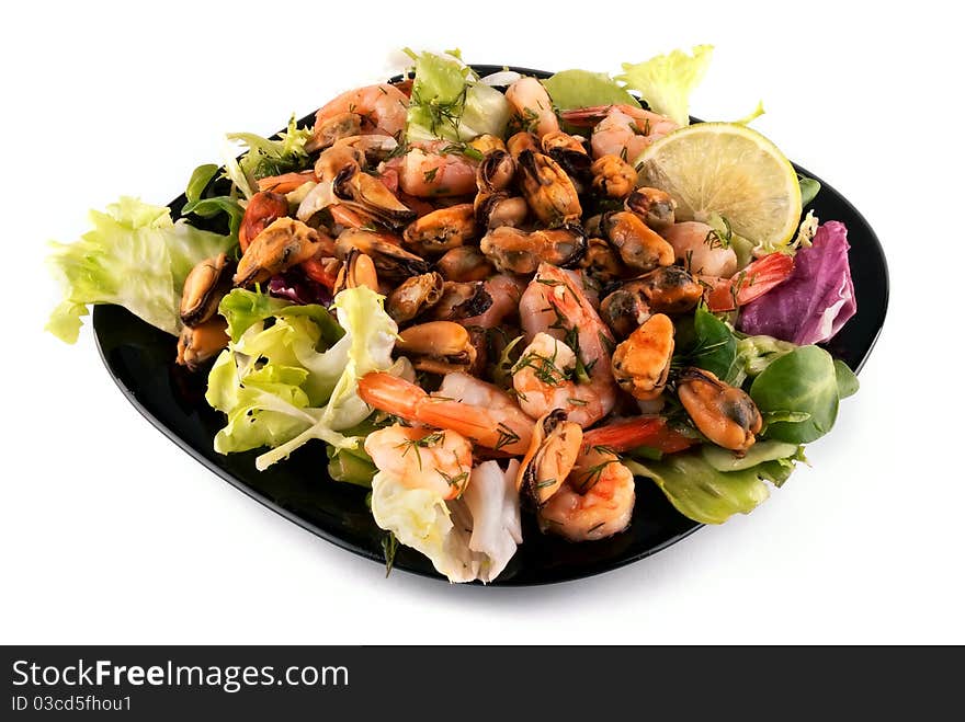 A salad with seafood on a black plate