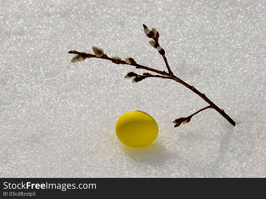 Yellow Easter egg on spring snow