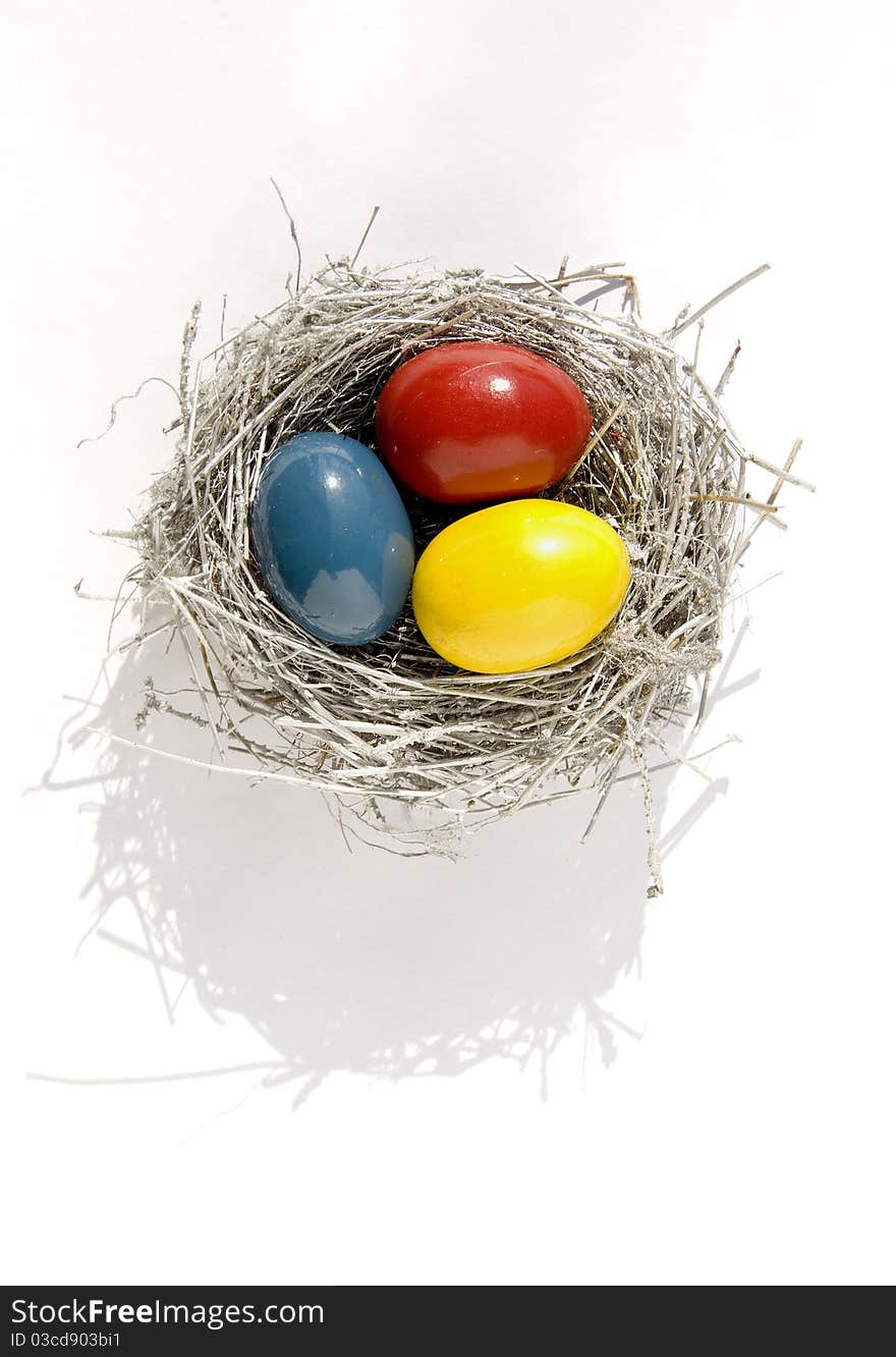 Nest with three color Easter eggs on white background. Nest with three color Easter eggs on white background