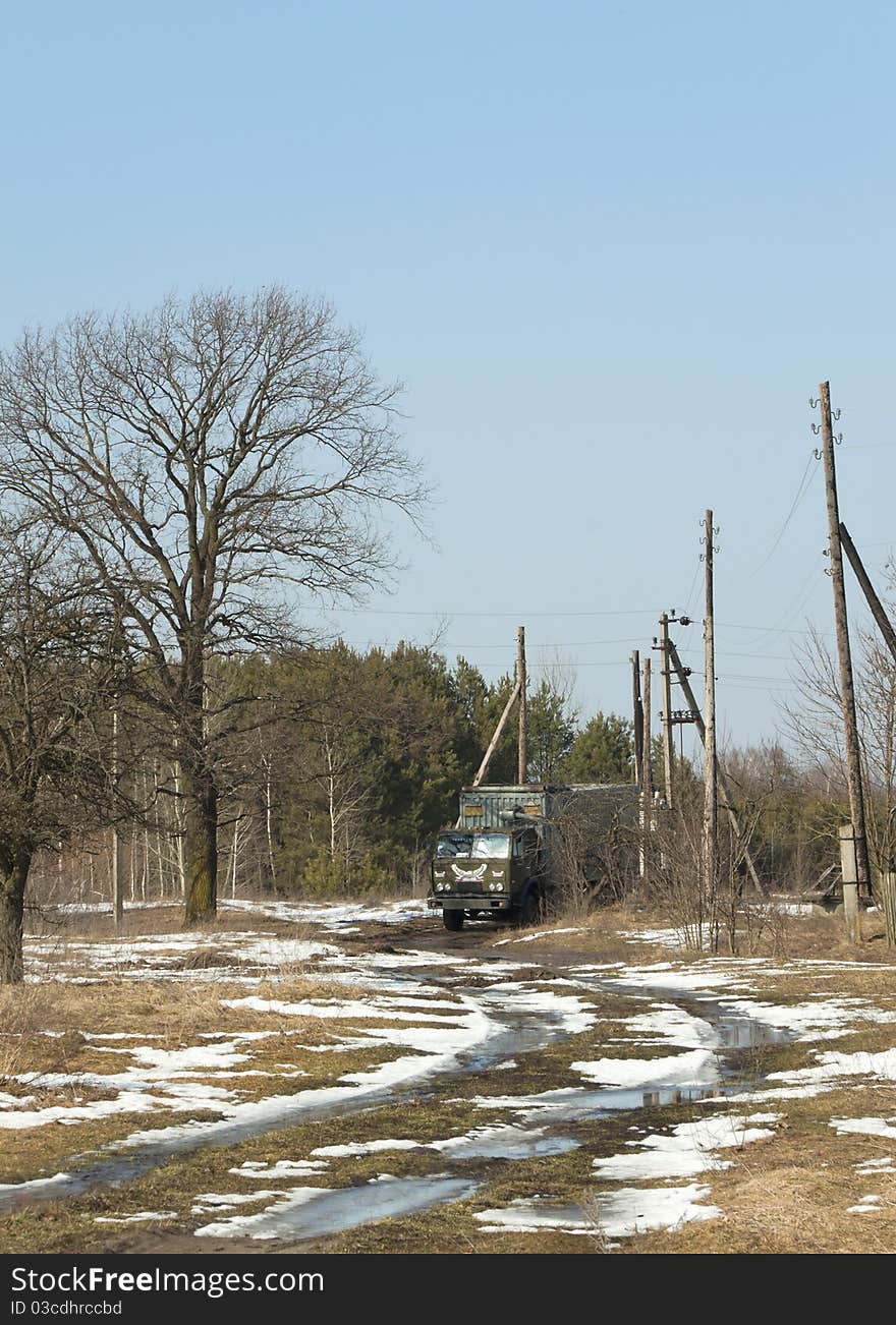 The lorry goes in the spring on a country road near wood. The lorry goes in the spring on a country road near wood