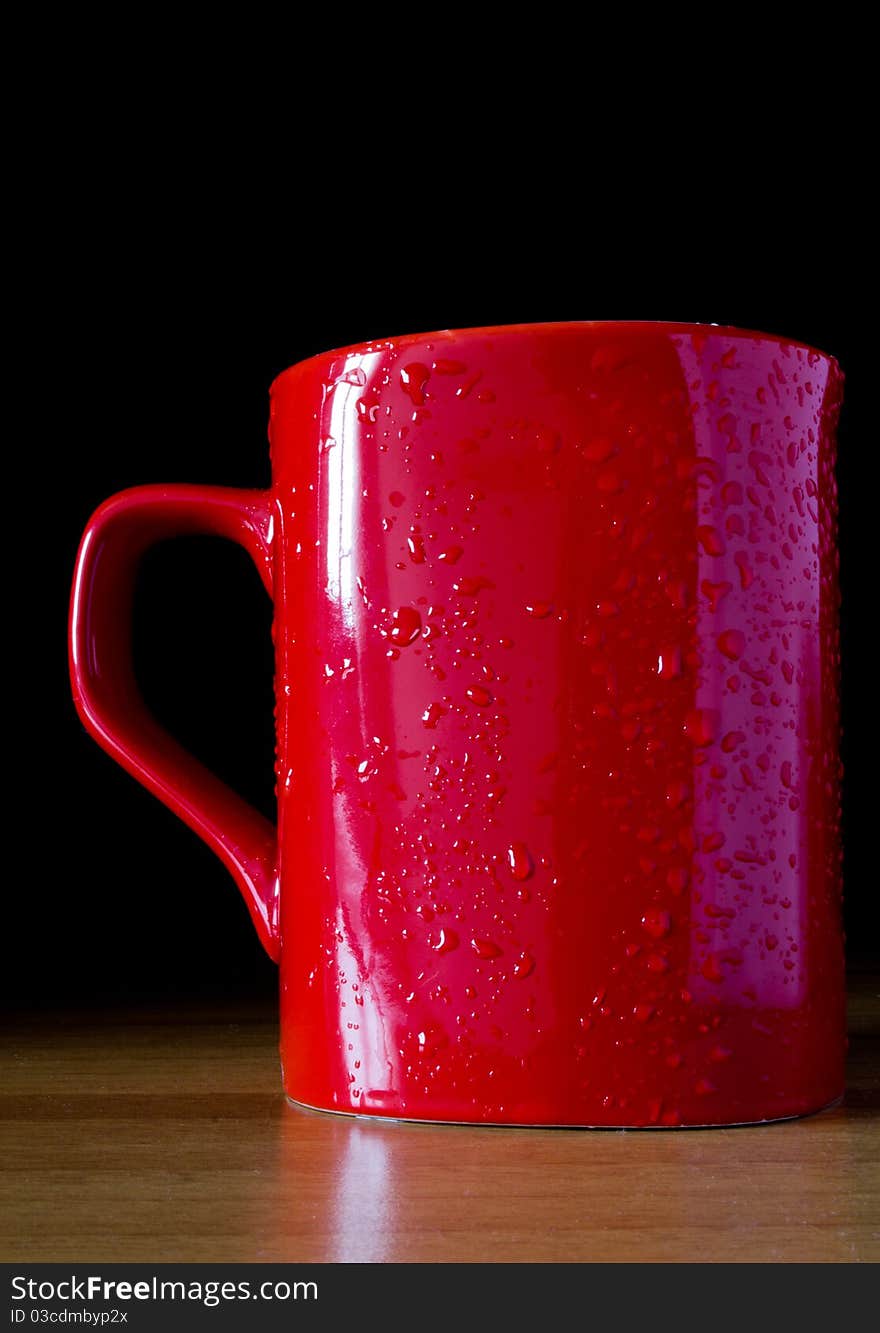 Red cup above table with black background