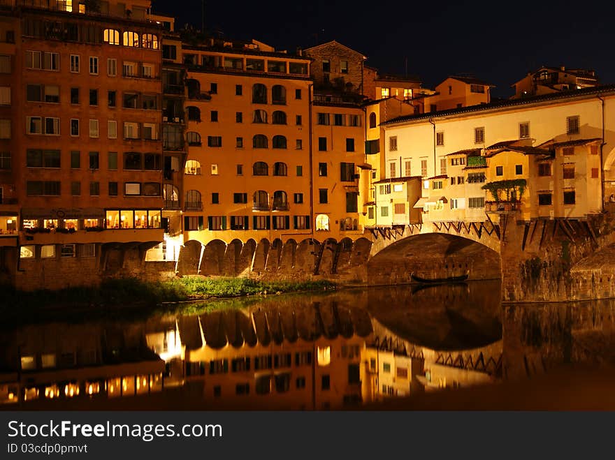 Reflections of the Ponte Vecchio in the River Arno by night in Florence, Italy