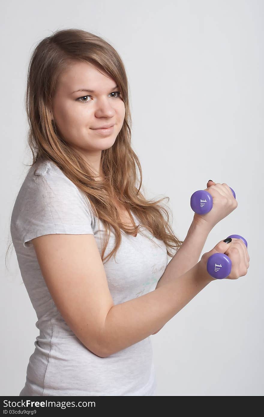 Girl on a white background with dumbbells in hand. Girl on a white background with dumbbells in hand