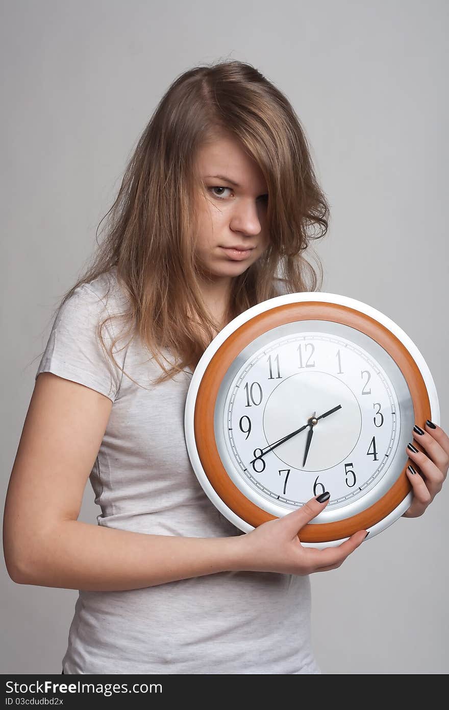 Sleeping girl on a white background with a big clock in the hands of which 6.40 am. Sleeping girl on a white background with a big clock in the hands of which 6.40 am