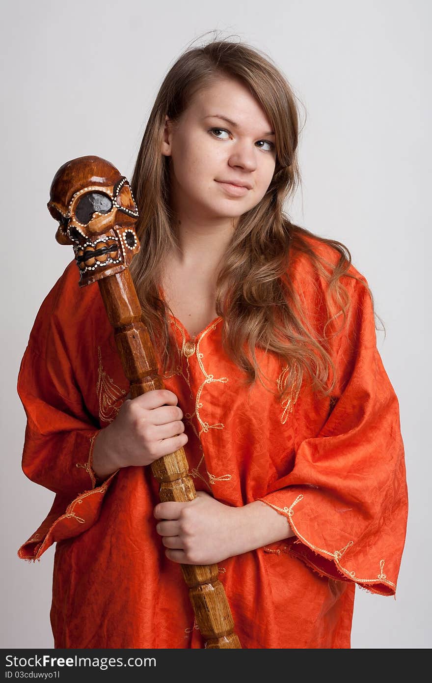 Girl in orange dress on a light background with a staff. Girl in orange dress on a light background with a staff