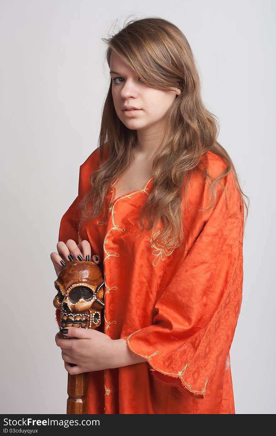 Girl in orange dress on a light background with a staff. Girl in orange dress on a light background with a staff