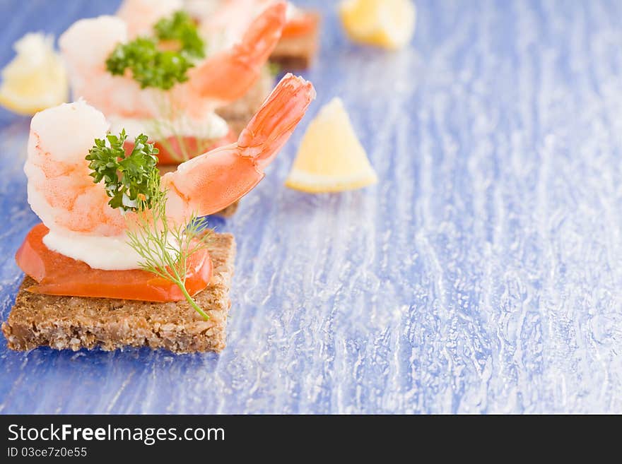 Photo of delicious starter made of prawns and tomatoes on black bread. Photo of delicious starter made of prawns and tomatoes on black bread