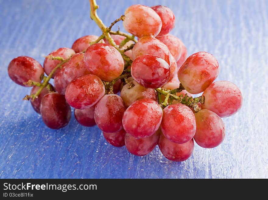 Photo of delicious red grape on blue glass table. Photo of delicious red grape on blue glass table