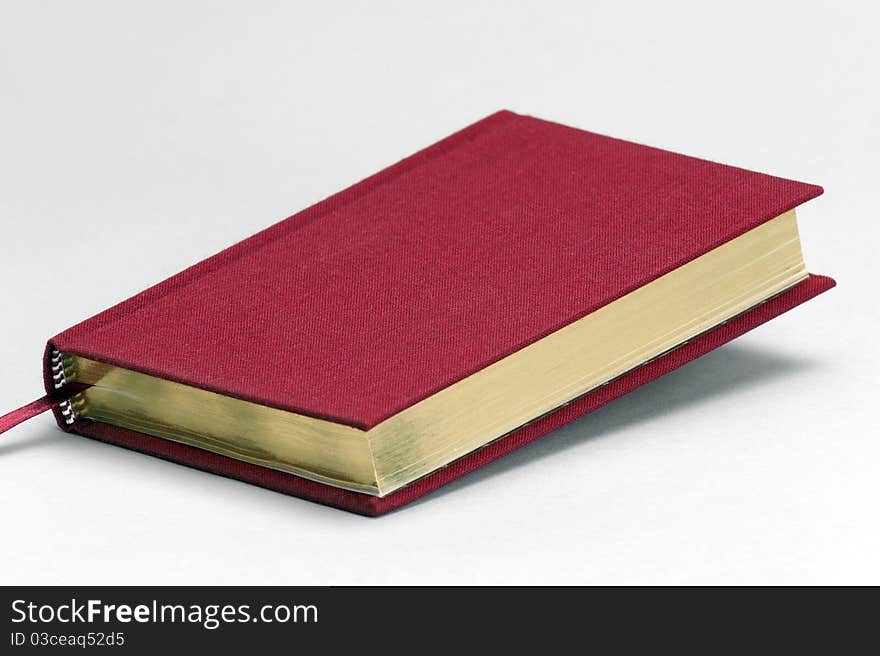 Red plain book with gold coloured pages on a light background. Red plain book with gold coloured pages on a light background