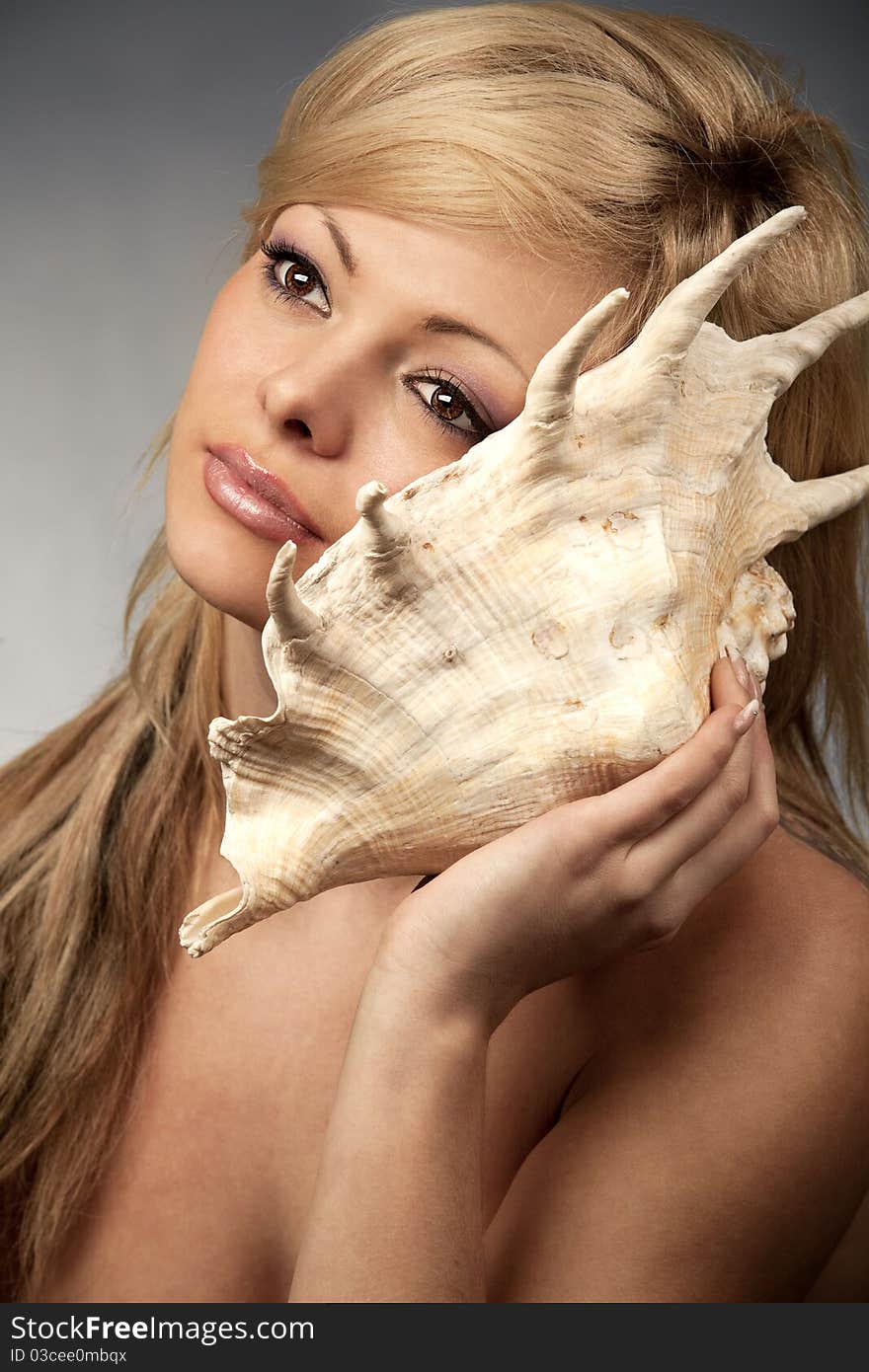 Female listening to the sea by a seashell