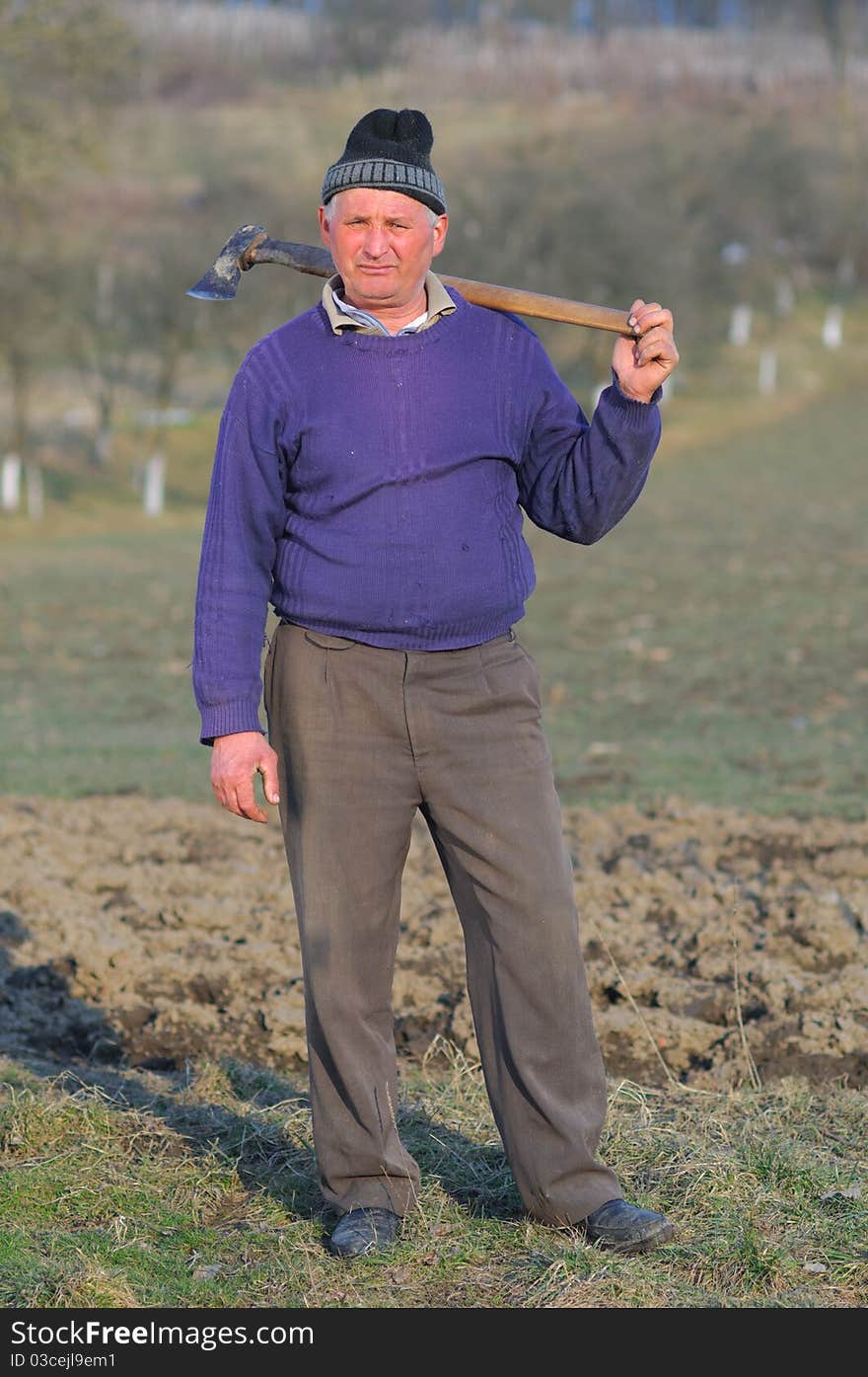 Posing woodcutter near the forest with a hatchet on his shoulder.